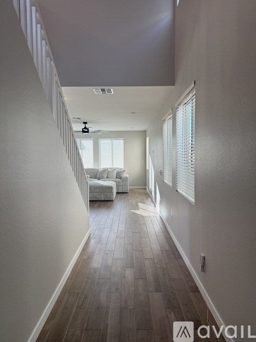 A long hallway with a couch and a fan.