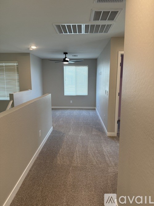 A carpeted hallway with a fan and a door on the right.
