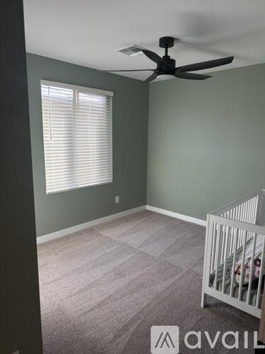 A baby's room with a crib and a fan.