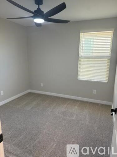 A room with a ceiling fan and a window with blinds.