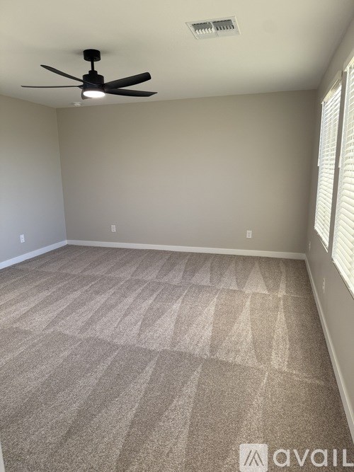 A room with a ceiling fan and carpeted floor.