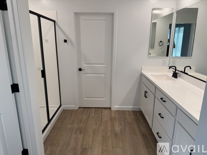 A bathroom with a white door, sink, and mirror.