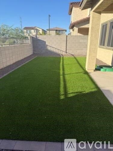 A backyard with a green lawn and a wall.