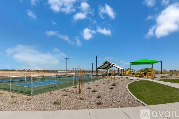 A tennis court with a green roofed pavilion and a white fence.
