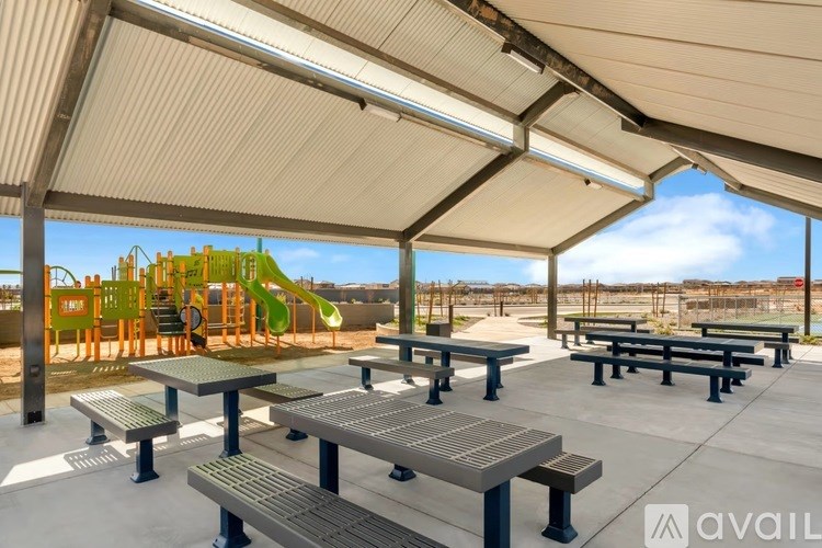 A playground with a slide and picnic tables under a covered area.