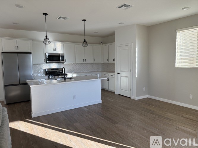 A kitchen with white cabinets and a wooden floor.