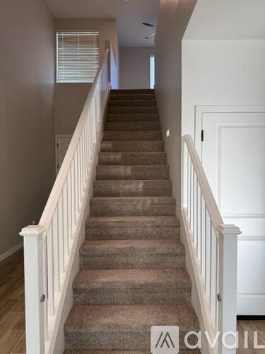 A staircase with beige carpet and white railings.
