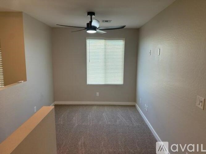 A room with a ceiling fan and a window with blinds.