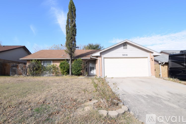 A house with a garage and a tree in front of it.