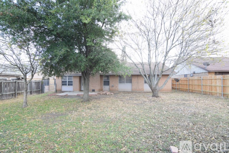 A backyard with a tree and a house in the background.