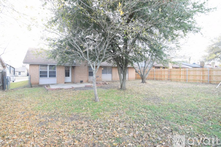 A tree in a yard with a house in the background.
