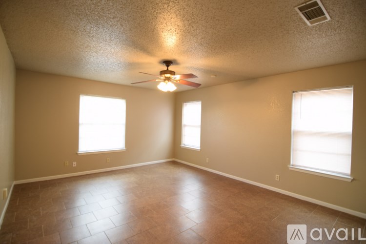 A room with a ceiling fan and two windows.