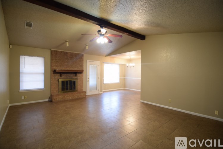 A spacious living room with a fireplace and a ceiling fan.