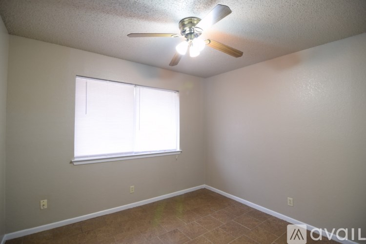 A room with a ceiling fan and a window letting in light.