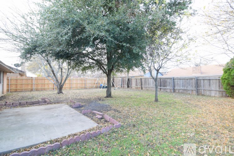 A backyard with a concrete patio and a fence.