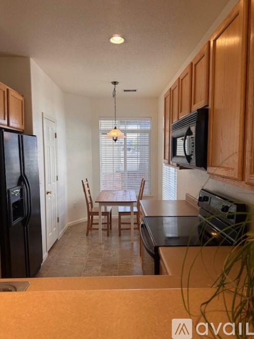 A kitchen with wooden cabinets and a black refrigerator.