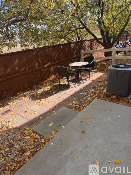 A patio with a table and chairs surrounded by a fence and trees.