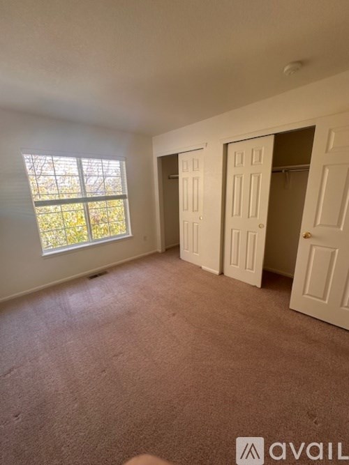 A room with a carpeted floor and a window with blinds.