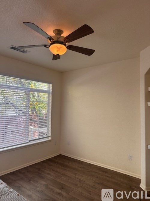 A room with a ceiling fan and a window with blinds.
