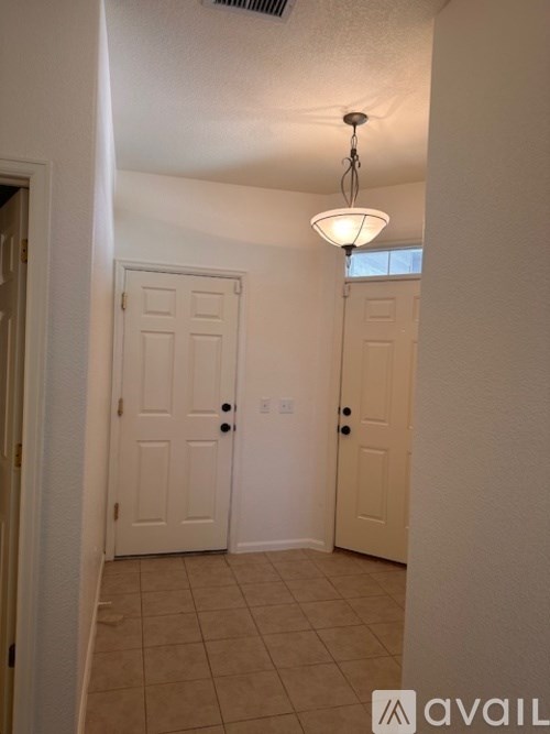 A hallway with two doors and a light hanging from the ceiling.