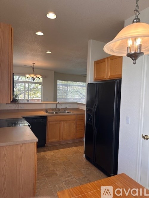 A kitchen with wooden cabinets and a black refrigerator.