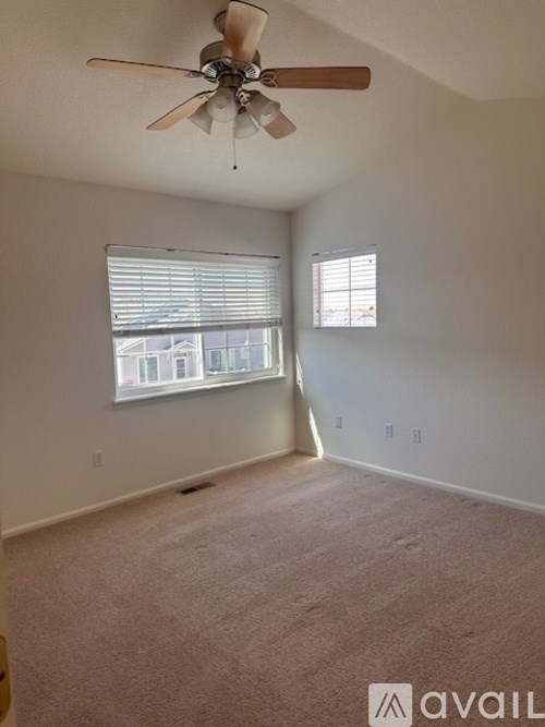 A room with a ceiling fan and carpeted floor.