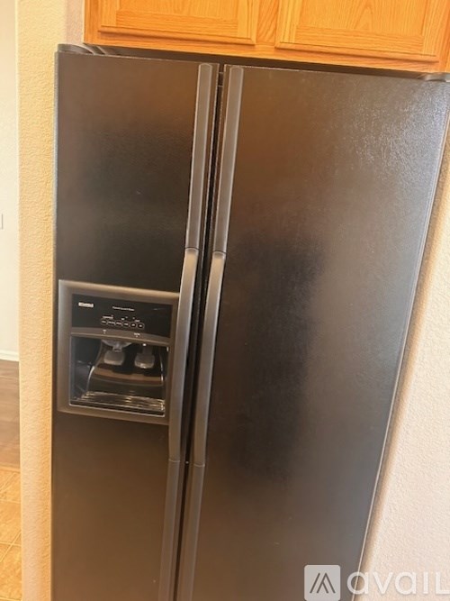 A black refrigerator with a water and ice dispenser in the middle.