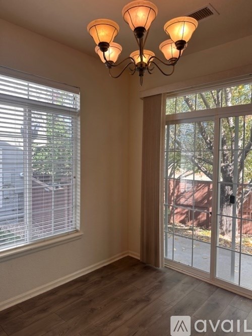 A room with a chandelier and a window with blinds.
