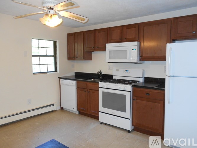 A kitchen with white appliances and wooden cabinets.