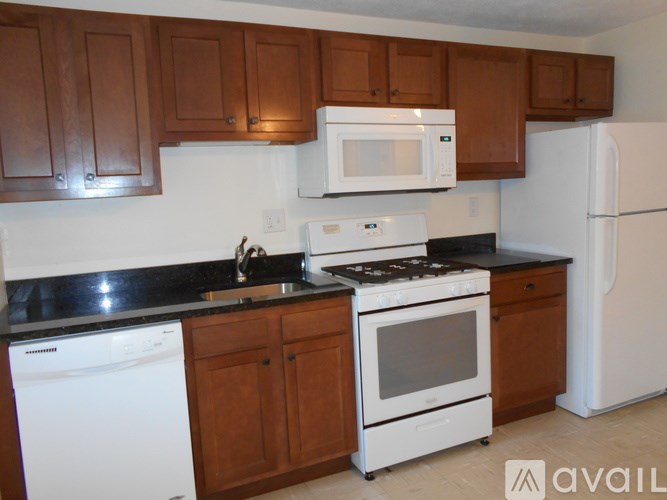 A kitchen with white appliances and brown cabinets.