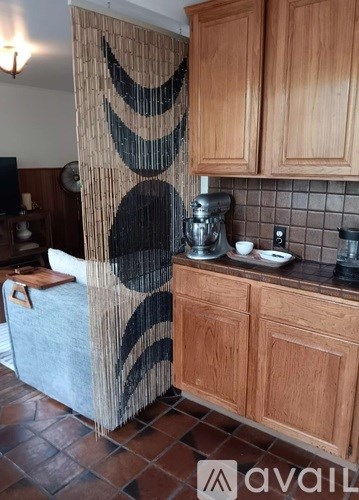 A kitchen with wooden cabinets and a curtain with black circles.