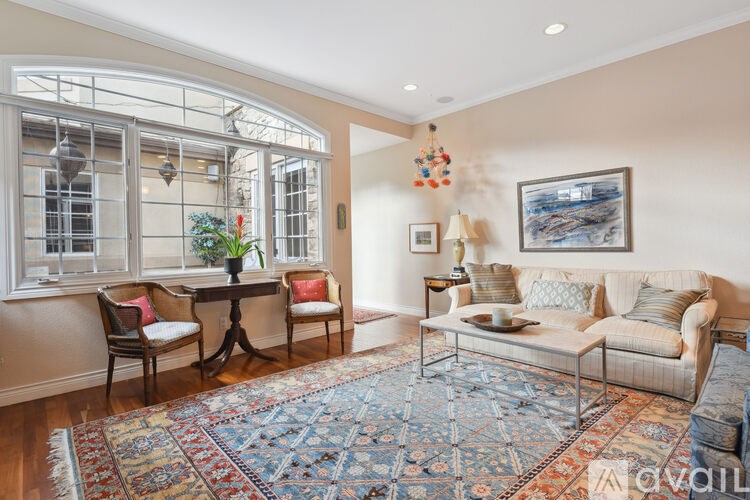 A living room with a couch, chairs, and a rug.