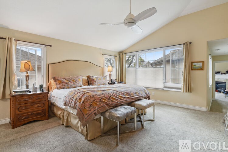 A bedroom with a large bed, a dresser, and a ceiling fan.