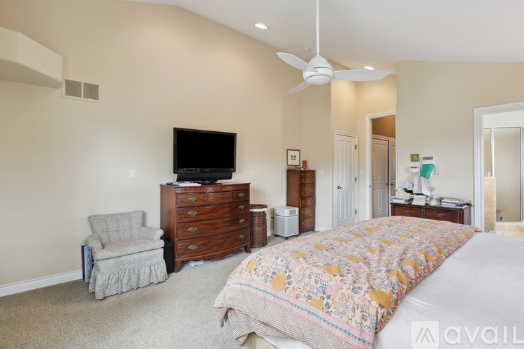 A bedroom with a large bed, a chair, and a television.