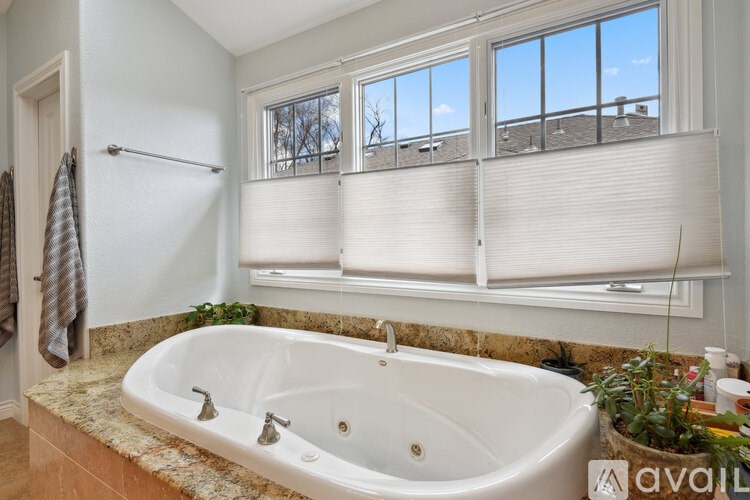 A bathroom with a large tub and a window with blinds.