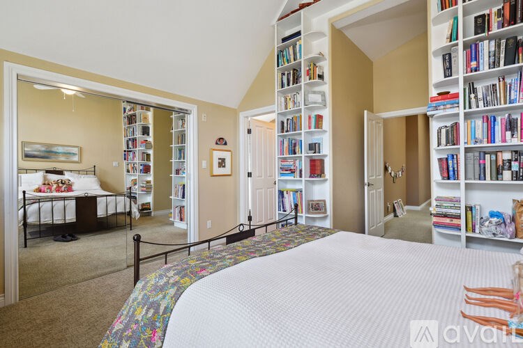 A bedroom with a large bed and a bookshelf filled with books.