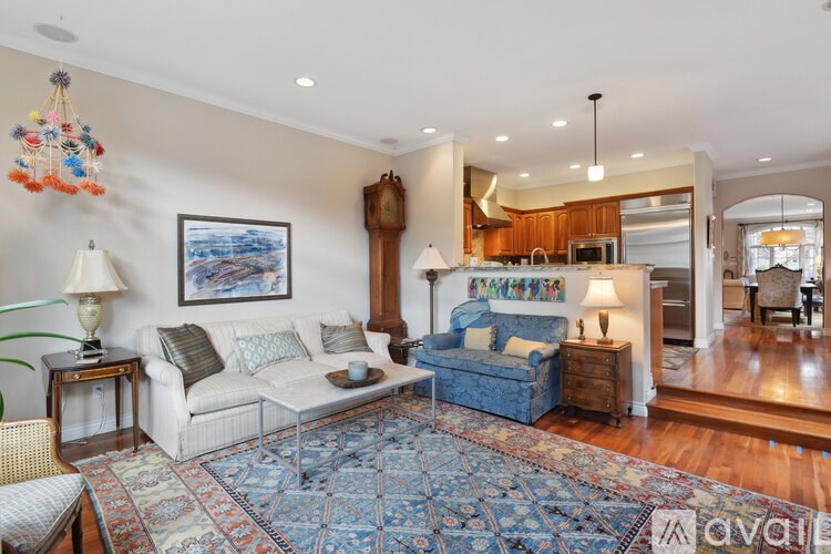 A living room with a white couch, a blue couch, and a rug.