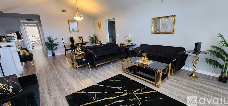 A living room with black couches and gold accents.