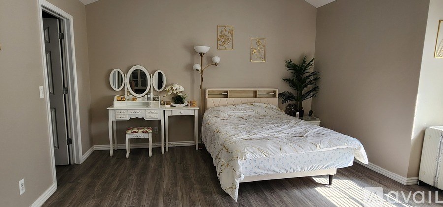 A bedroom with a bed, nightstand, and a vanity table with a mirror.