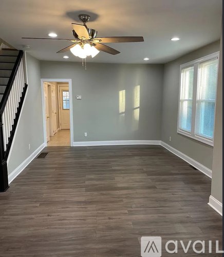 A spacious room with a ceiling fan and wooden flooring.