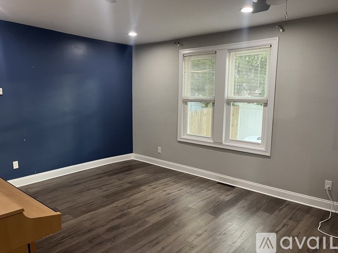 A room with a wooden floor and a window with blinds.