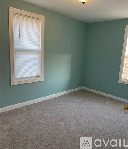 A room with a window and a carpeted floor.