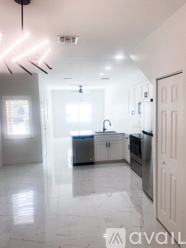 A kitchen with white cabinets and a marble floor.