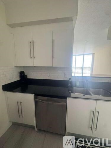 A kitchen with white cabinets and a black countertop.