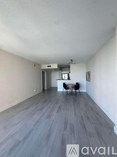 A pool surrounded by palm trees and a city skyline in the background.