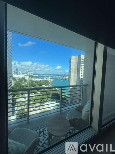 A balcony with a table and chairs overlooking a cityscape.