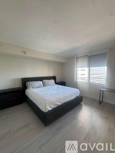 A bedroom with a large bed and a window with blinds.