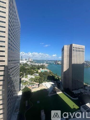 A view from a high-rise building looking down at a cityscape with a large body of water in the distance.