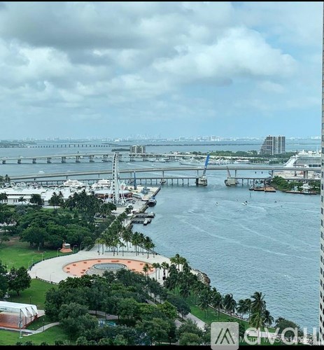 A view of a bridge over a body of water with boats and a city in the distance.