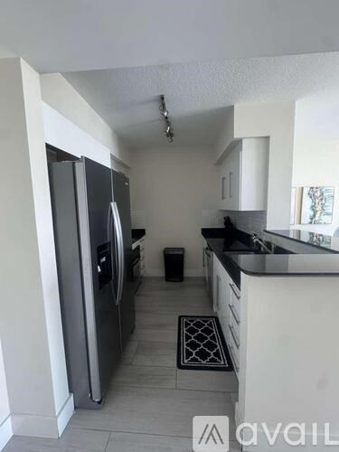 A kitchen with a refrigerator, sink, and cabinets.